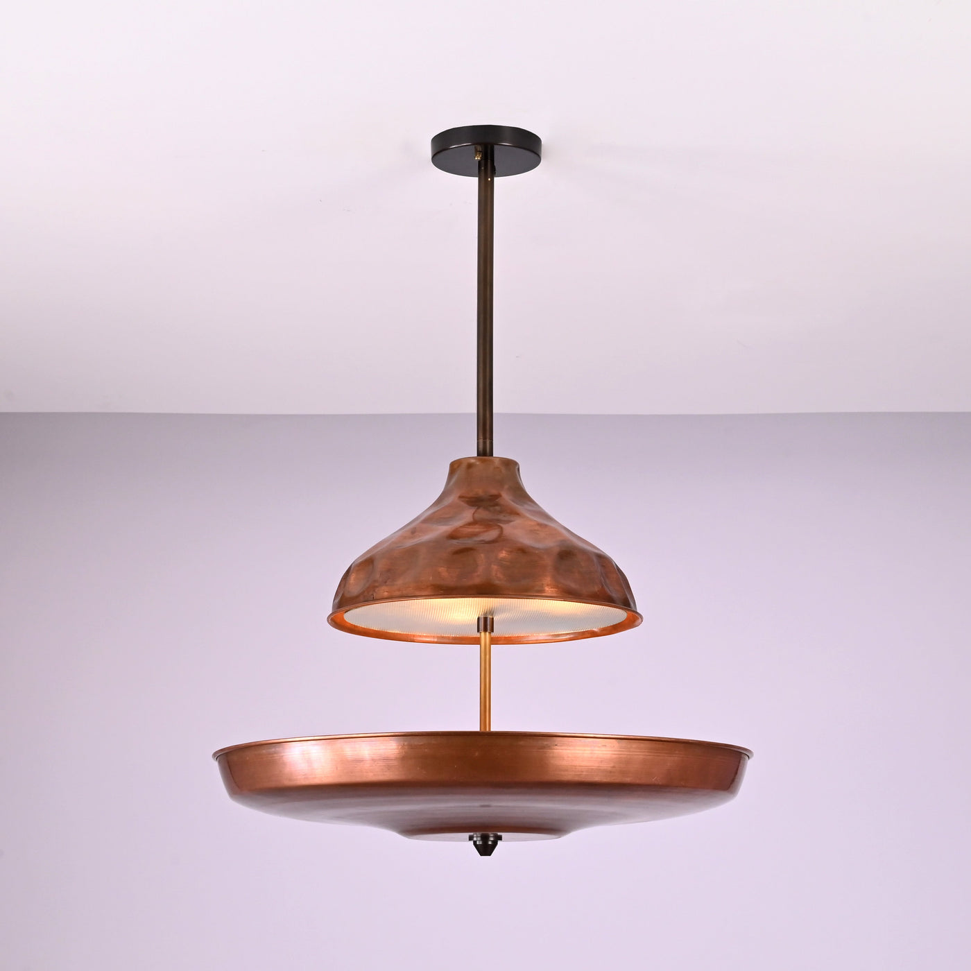 Modern copper disc chandelier with warm indirect lighting and sculptural bowl shade, handcrafted from solid brass