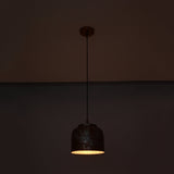 Cora pendant light glowing warmly from below, highlighting the compact drum shade and textured copper finish