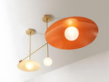 Illuminated brass ceiling light with disc-shaped shades emitting warm indirect light, highlighting minimalist geometry and premium handcrafted brass finish.