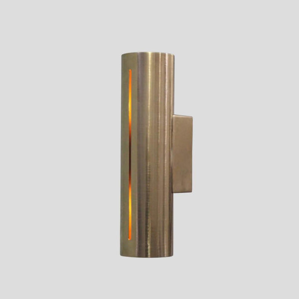 Handmade cylindrical brass wall sconce with vertical glowing slit design, crafted by Brass Leaf Studio for modern and industrial interiors.