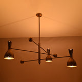 Close-up of Diabolo brushed brass chandelier showcasing perforated bowl shades and warm light diffusion.
