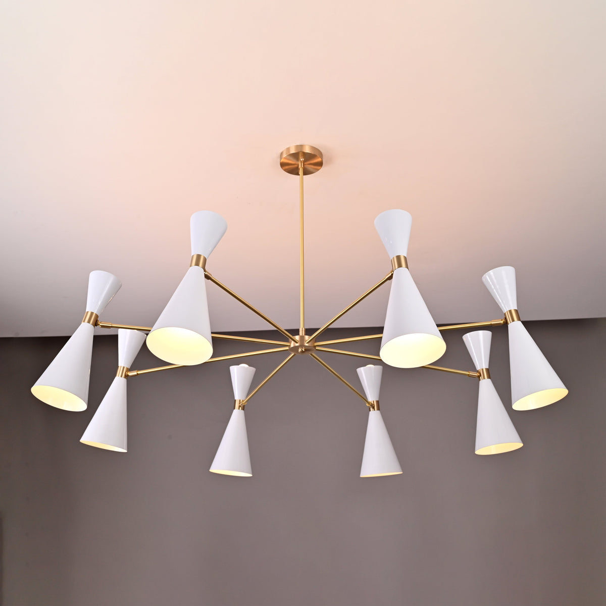 Elegant Diabolo chandelier featuring 16 white double-cone shades on a brass frame, modern designer lighting by Brass Leaf Studio.