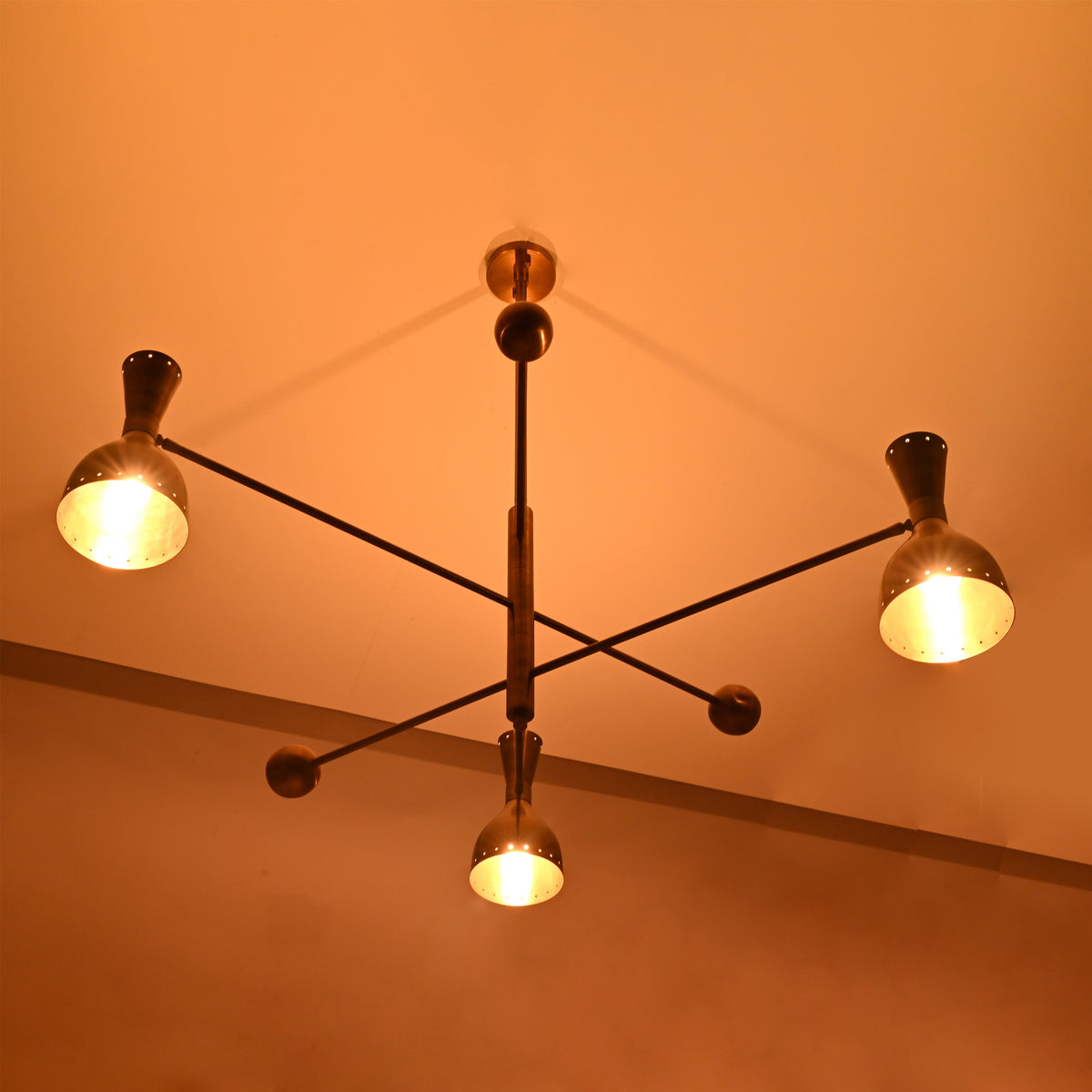 Diabolo industrial-style brass chandelier enhancing interior ambiance with sculptural form and warm handcrafted lighting.