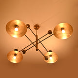 Top view of Diabolo brass chandelier illuminated in warm ambient light with sculpted bowl shades creating a dramatic glow.
