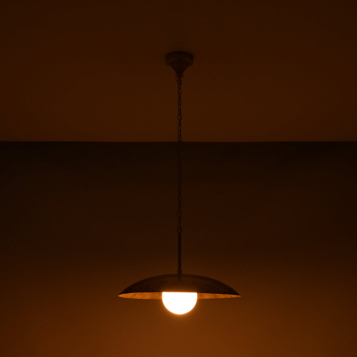 Dome disc pendant light with 20 inch shade and glowing 6 inch glass globe on dark background