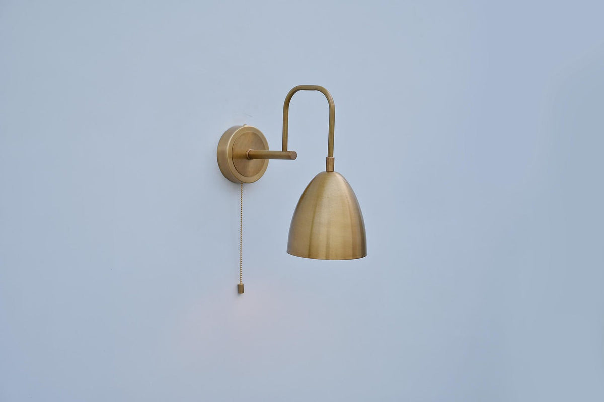 Dome-shaped brass wall light with minimal silhouette and pull chain, handcrafted in India by Brass Leaf Studio.