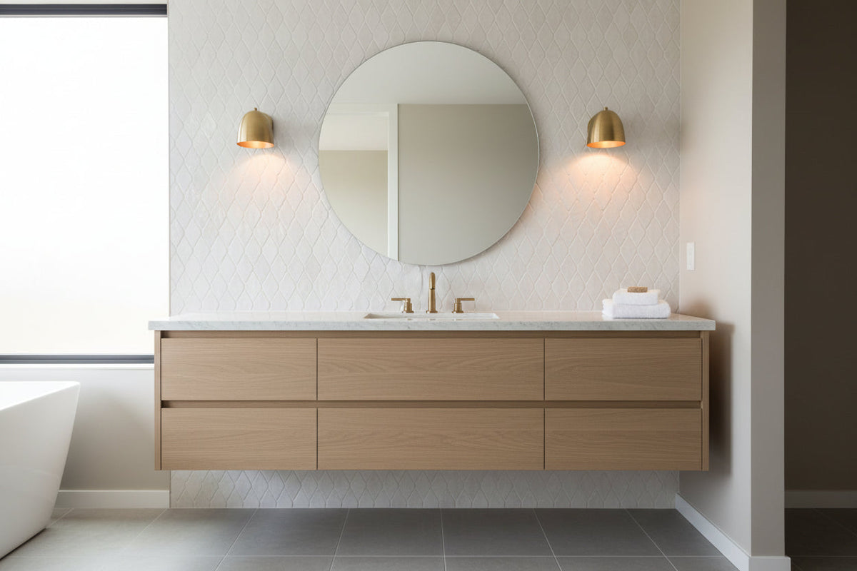 A modern dome-shaped wall sconce with a brushed brass finish, mounted on a dark wall and casting a warm golden light downward.