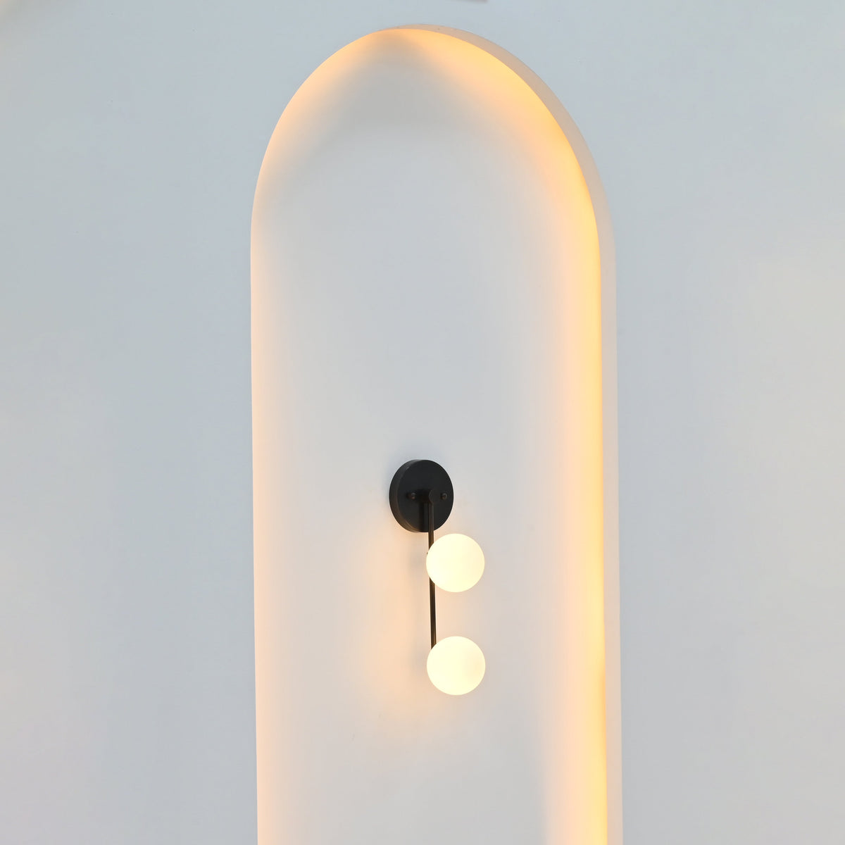 Two-light globe wall sconce illuminated with soft warm ambient light for bedroom, hallway, vanity, or living room interiors