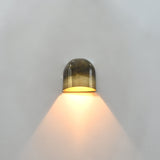 Compact dome wall light with dual patina brass surface creating a warm cone of light on the wall