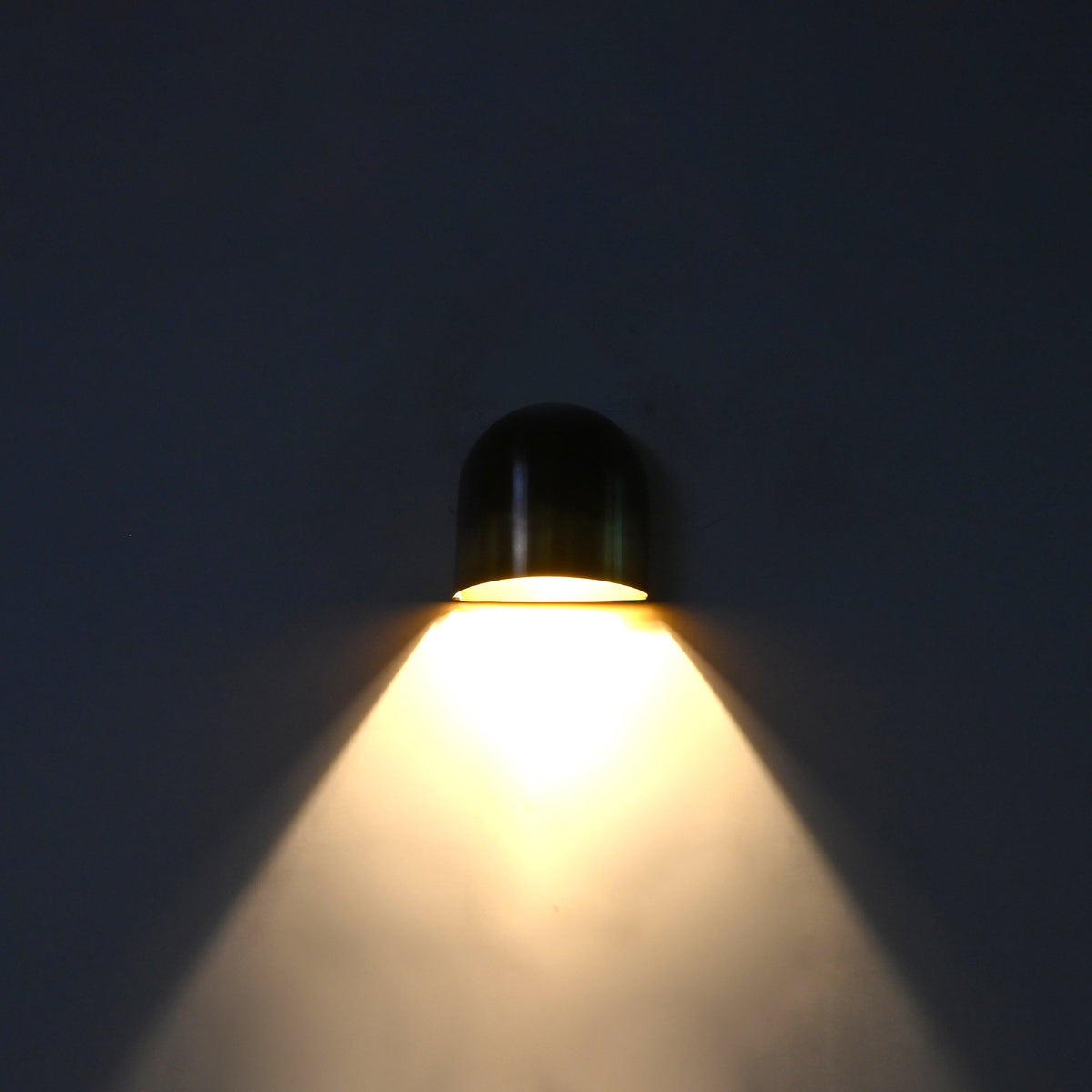Closeup of dual tone brass wall sconce showing dark aged upper patina and warmer brass lower section
