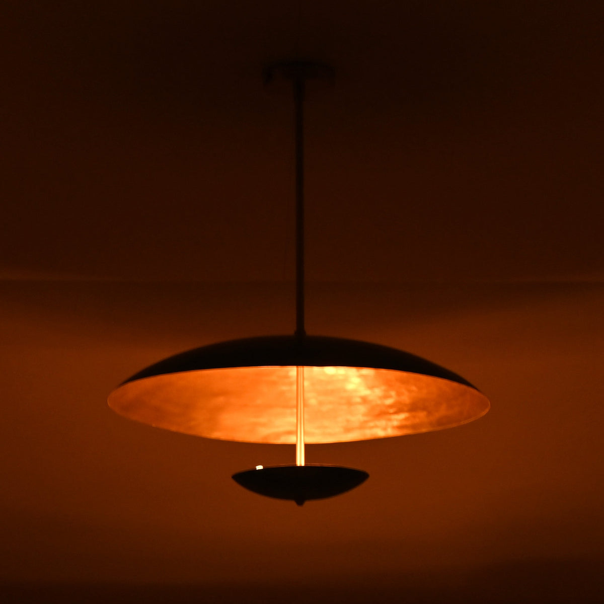 Warmly lit emerald green brass chandelier casting soft golden ambient light across ceiling interior