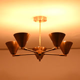 Bottom view of five-light brass cone chandelier highlighting warm indirect lighting and symmetrical arm layout.