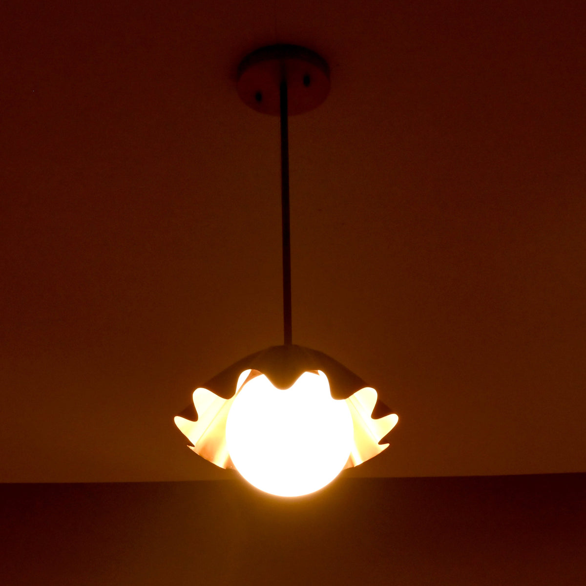 Fluted brass pendant light creating soft uplifting illumination in a moody evening environment.