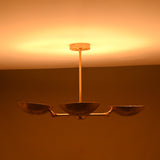 Four-bowl brass chandelier photographed in low lighting, showing deep golden glow and atmospheric ceiling illumination.