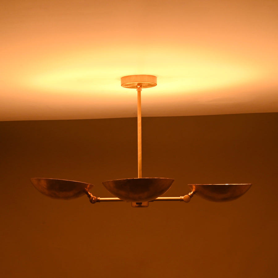 Front angle view of handcrafted solid brass chandelier with four hammered bowl shades and central brass rod suspension.