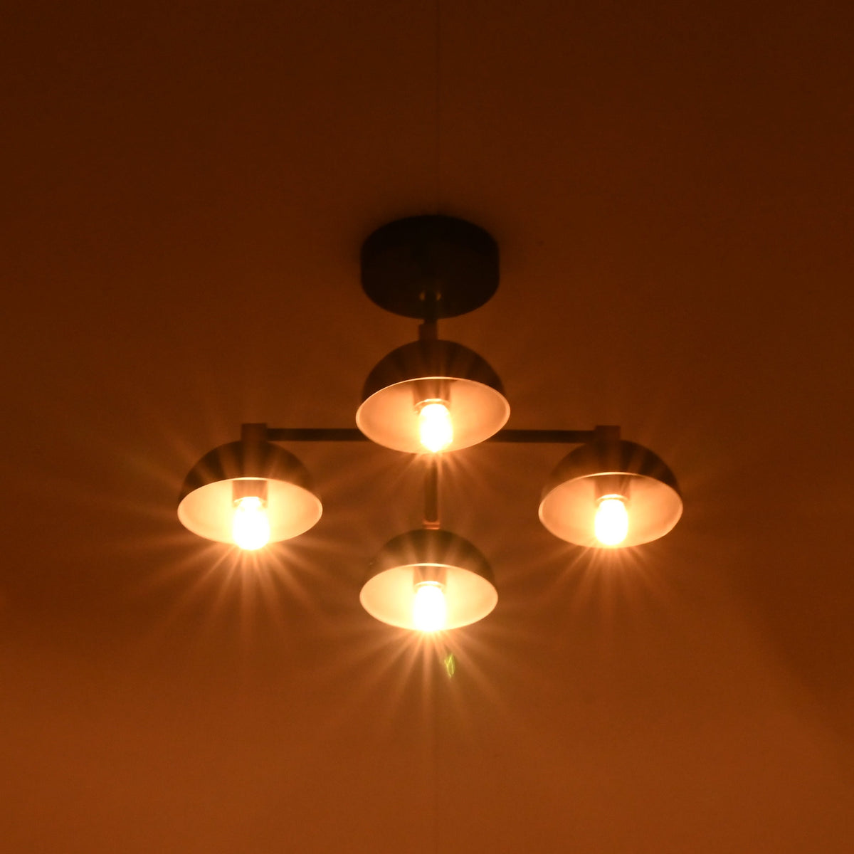 Four light brass ceiling chandelier producing rich warm glow and dramatic lighting effects in dark room.