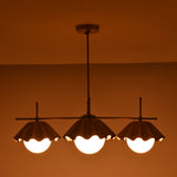 Bottom view of four-light brass chandelier showcasing warm indirect lighting and scalloped shade edges.