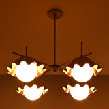Top view of four-light brass chandelier glowing warmly with sculpted bowl-shaped shades.