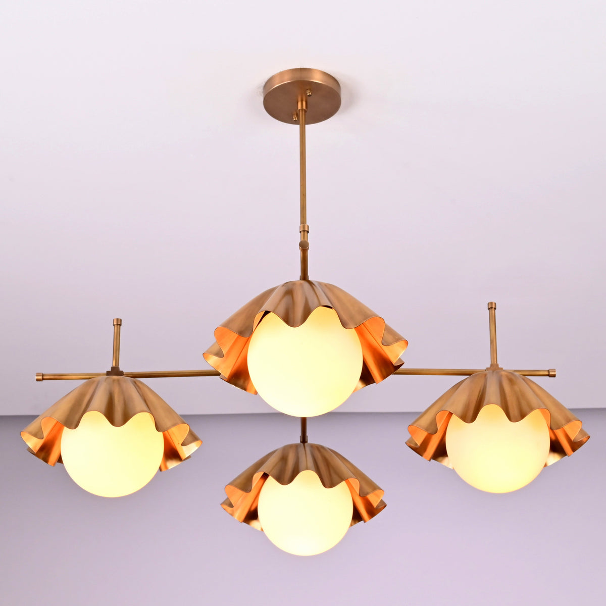 Angled view of four-light brushed brass chandelier highlighting sculpted shade details and craftsmanship.