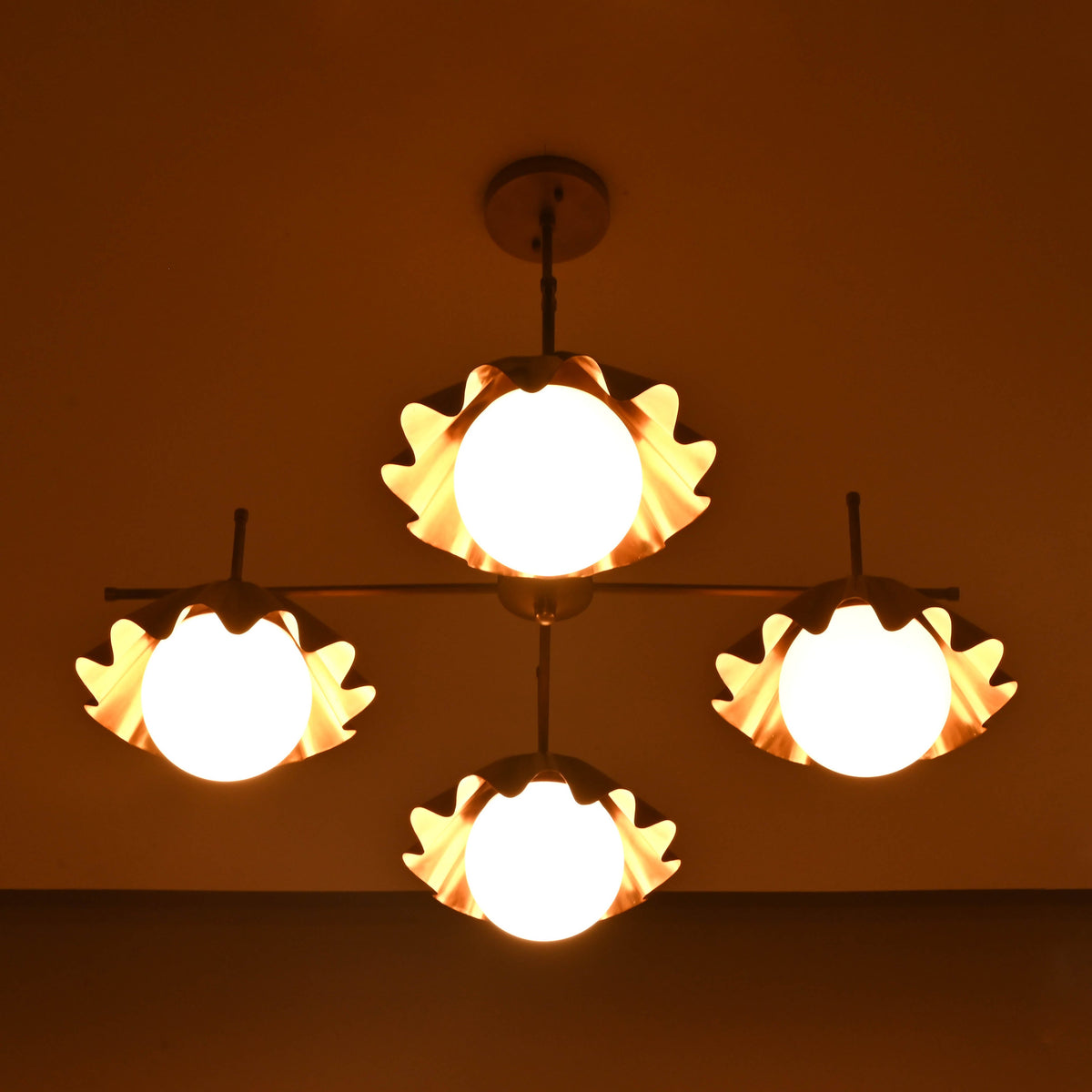 Four-light brushed brass chandelier casting soft evening lighting with sculptural fluted shades.