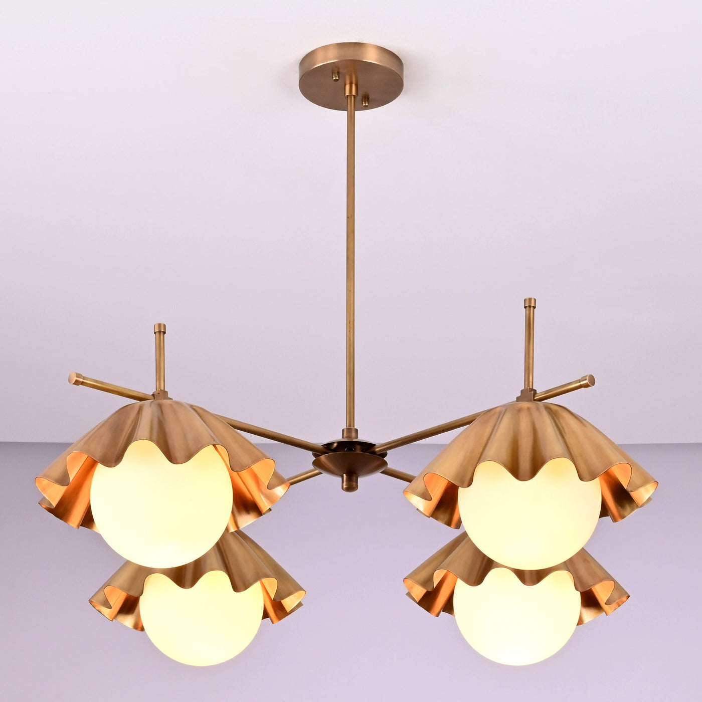 Four-light brushed brass chandelier with sculpted bowl shades and warm ambient lighting.