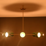 Close up of green bowl shaped metal shade on brass sputnik chandelier showing smooth finish and warm bulb reflection