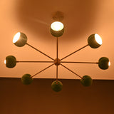 Green bowl sputnik chandelier casting warm indirect light across ceiling with soft modern ambiance