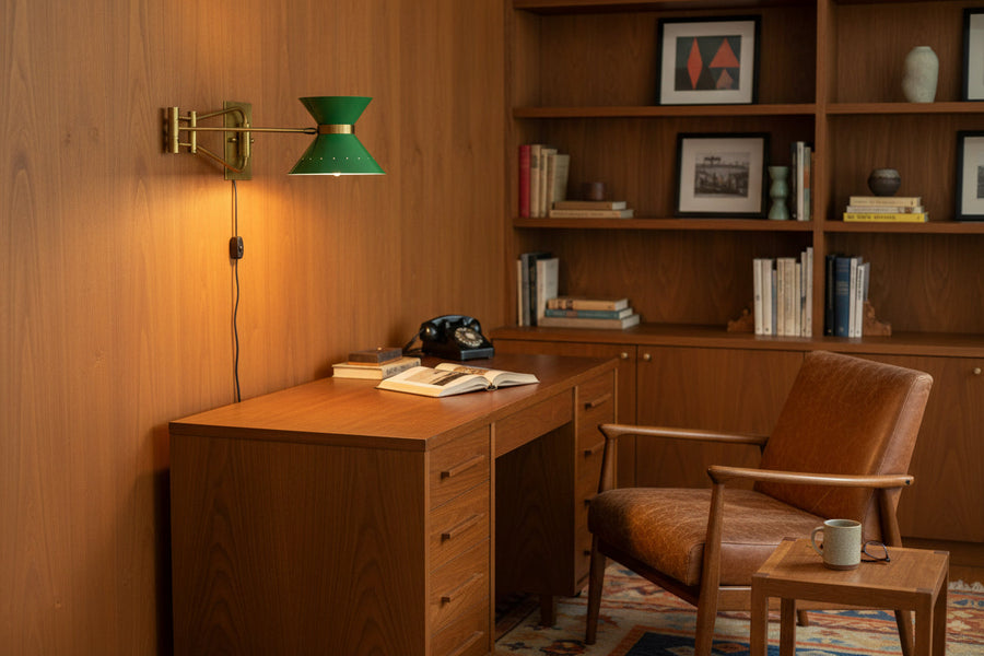 Movable arm brass wall light shown illuminated with green double cone shade and soft warm lighting