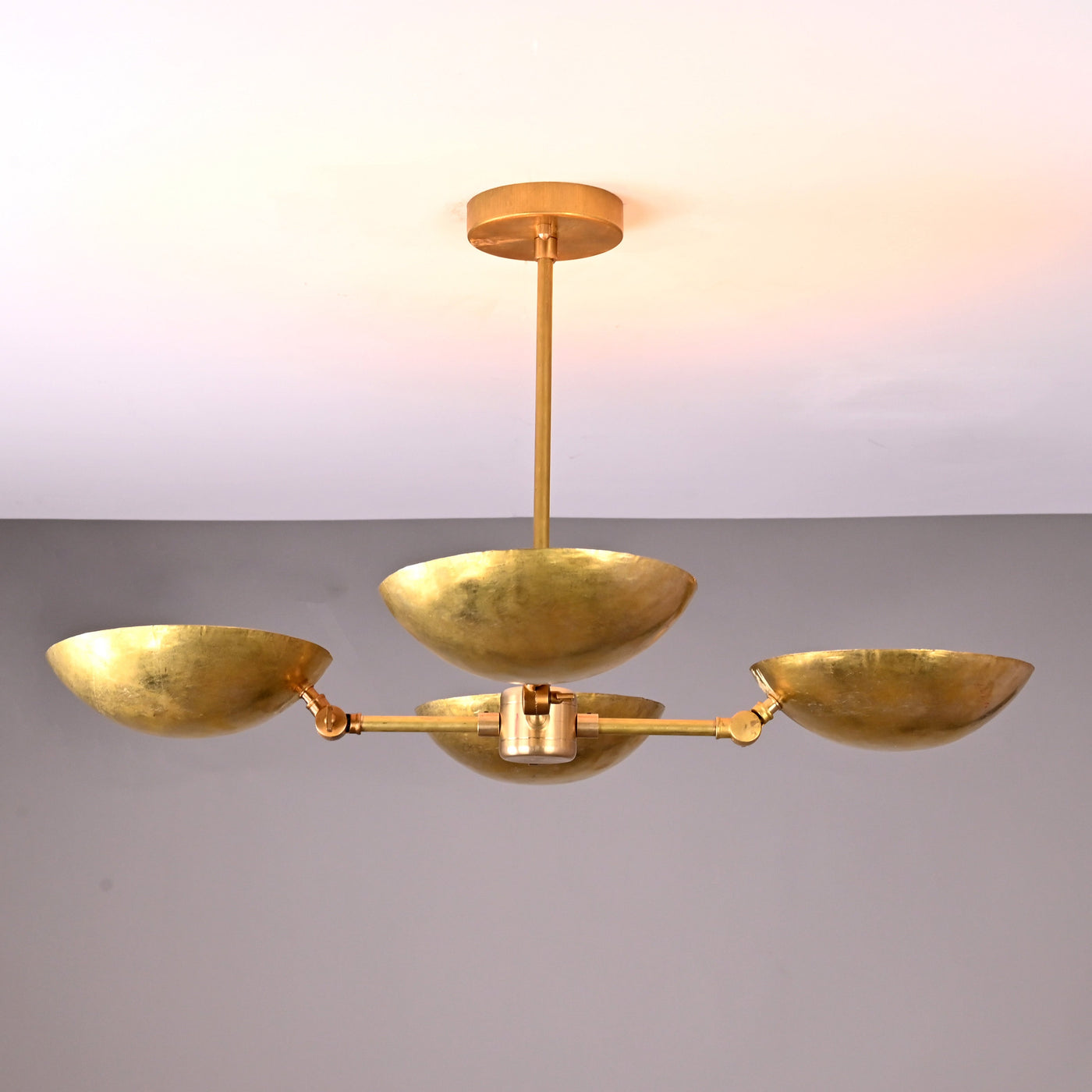 Front angle view of handcrafted solid brass chandelier with four hammered bowl shades and central brass rod suspension.