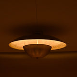 Handcrafted brass disc light with soft inner glow highlighting its smooth circular form in a dimly lit room
