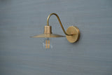 Angled view of handcrafted brass gooseneck wall sconce featuring curved arm and open bulb design for warm ambient lighting.