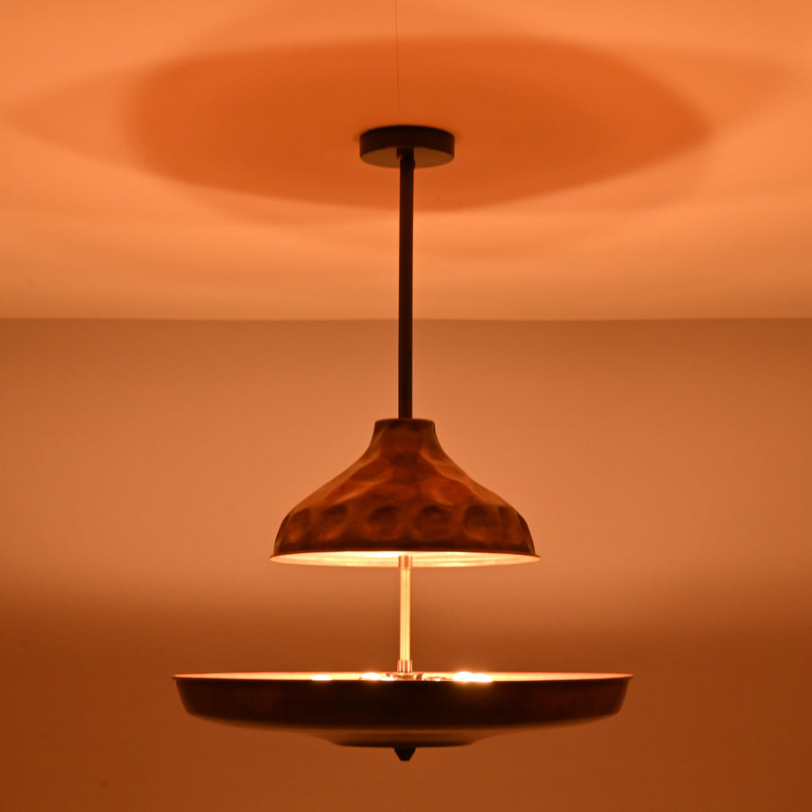 Modern copper disc chandelier with warm indirect lighting and sculptural bowl shade, handcrafted from solid brass