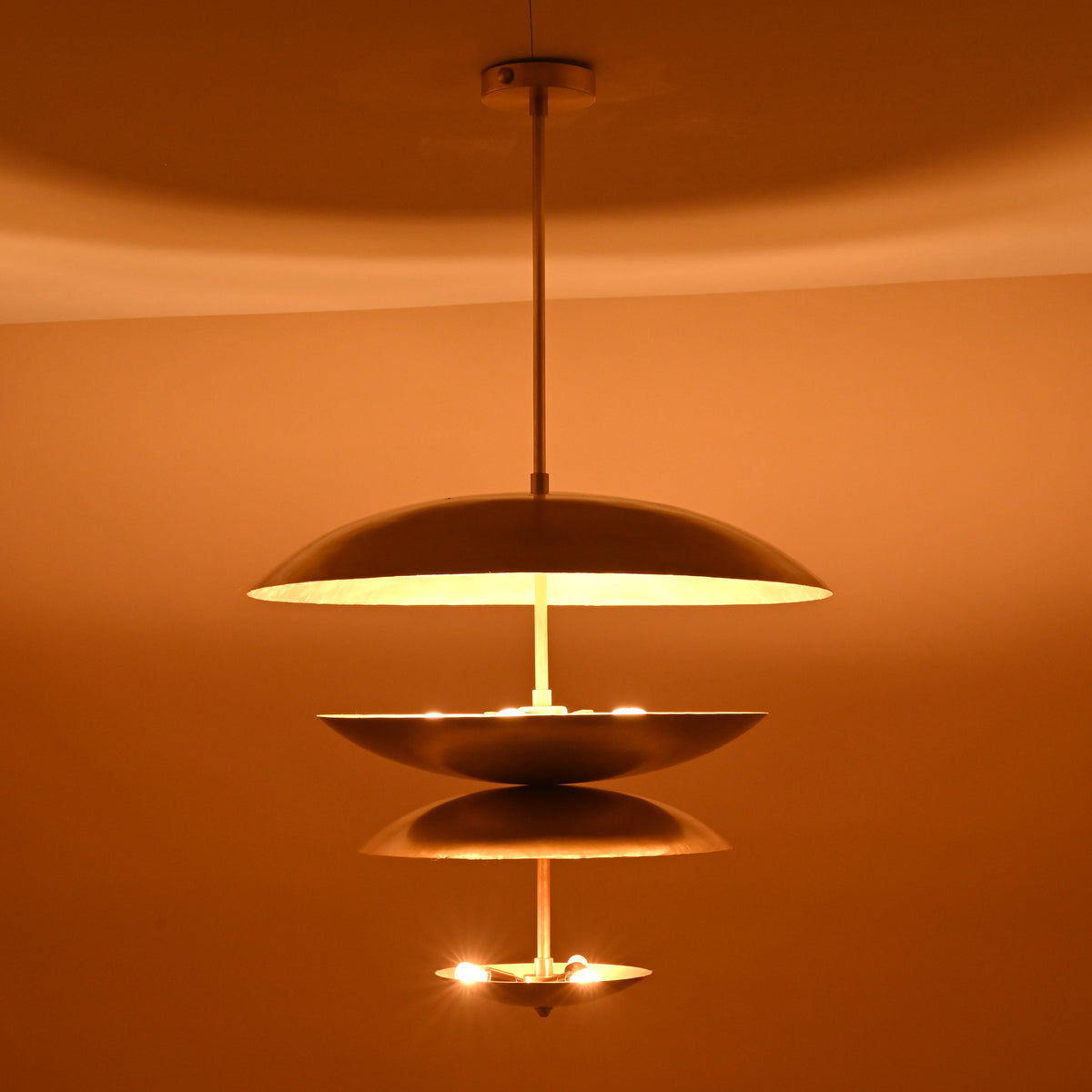 Handmade layered brass pendant with 8-light arrangement casting golden radiance