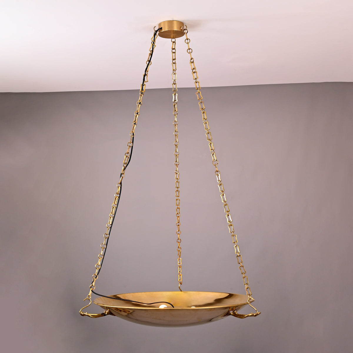 Handmade brass bowl chandelier with sculpted chain suspension in a modern interior