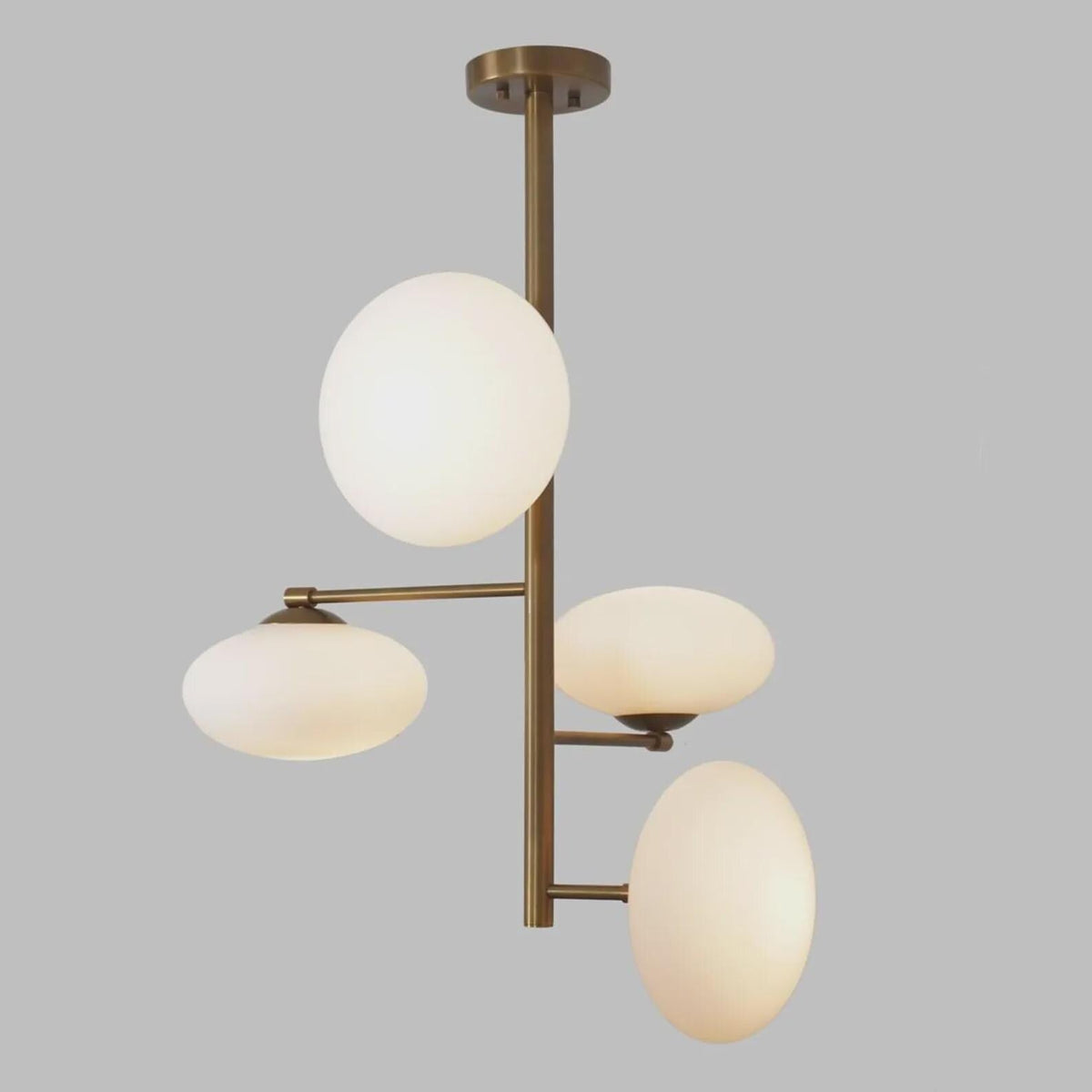 Handmade brass ceiling light with four milky glass globes, designed to create warm ambient illumination in modern interiors.