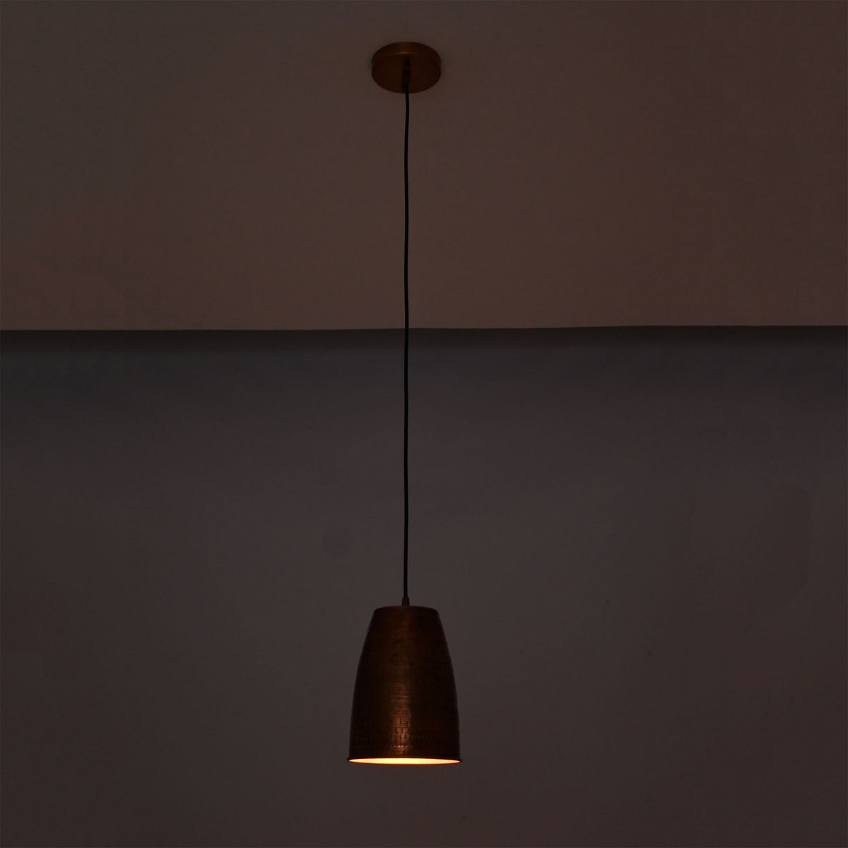 Hudson Hammered Copper Bell Pendant Light illuminated with warm downward lighting for ambient interiors.