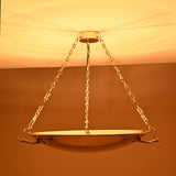 Warm indirect uplight from brass bowl chandelier creating atmospheric ceiling reflections