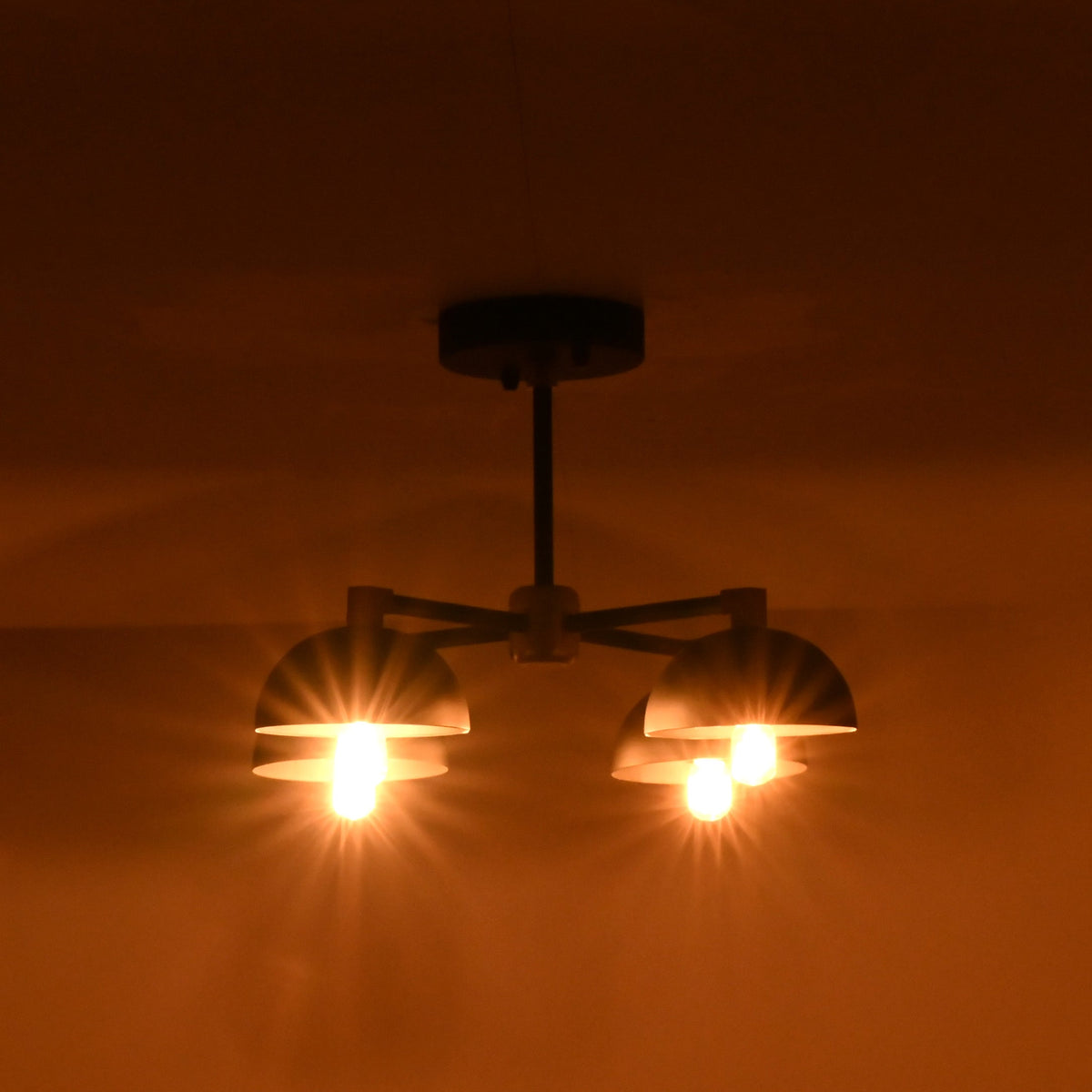 Industrial brass ceiling light creating soft uplifting light patterns in a moody evening environment.