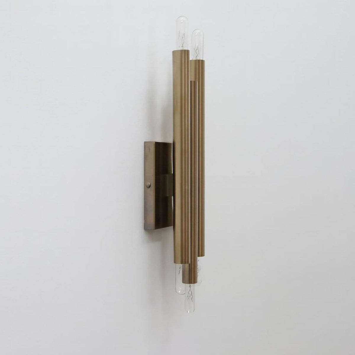 Industrial solid brass tube wall light with vertical cylinder design and exposed bulbs side angle view