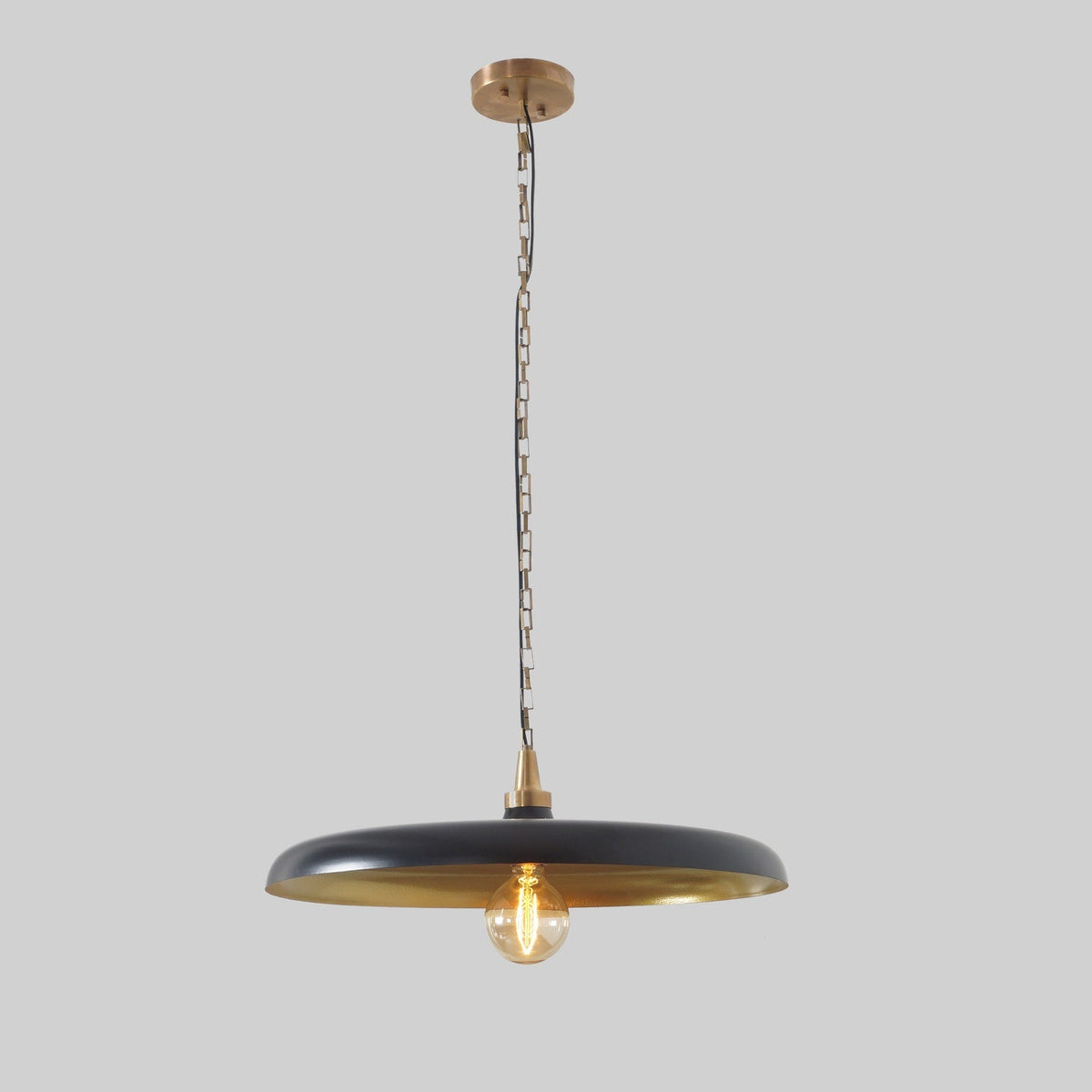 Interior view of dome pendant lamp with green enamel finish and warm glowing bulb