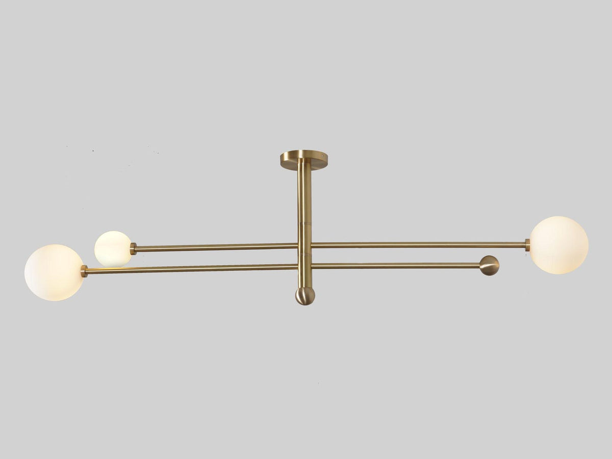 Industrial modern brass 3-light flushmount ceiling fixture with long brass rods and globe diffusers.