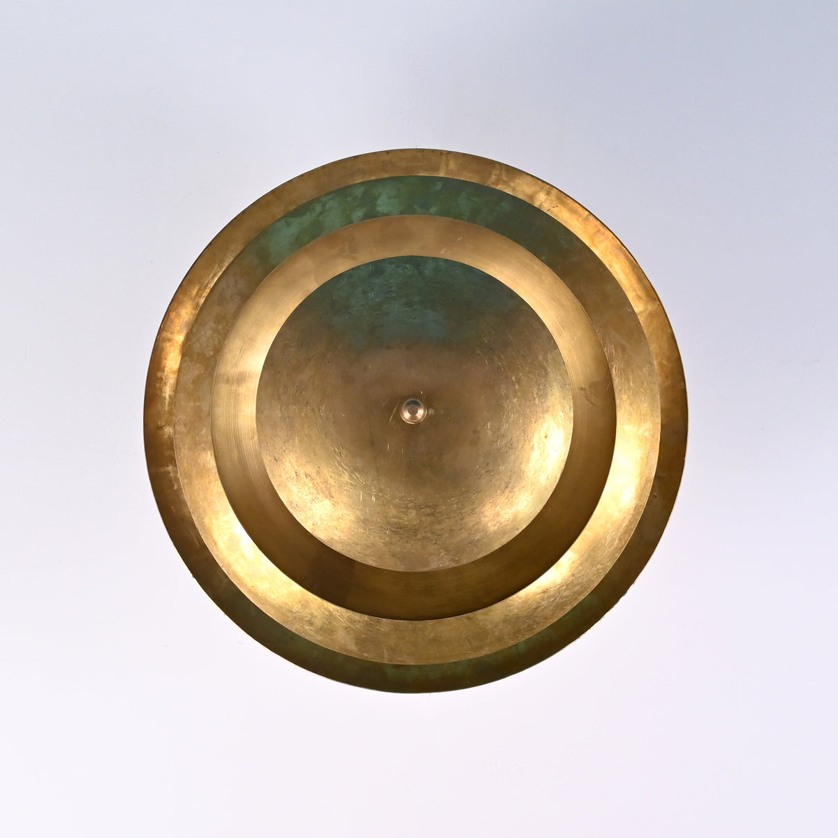 Underside view of modern brass disc ceiling light highlighting symmetrical layered bowl construction.