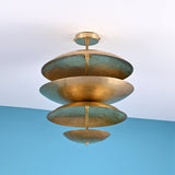 Angled view of modern layered brass ceiling light with sculpted bowl shades creating soft ambient indirect lighting.