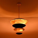 Layered brass and black disc chandelier emitting soft ambient glow, ideal for dining rooms and living spaces