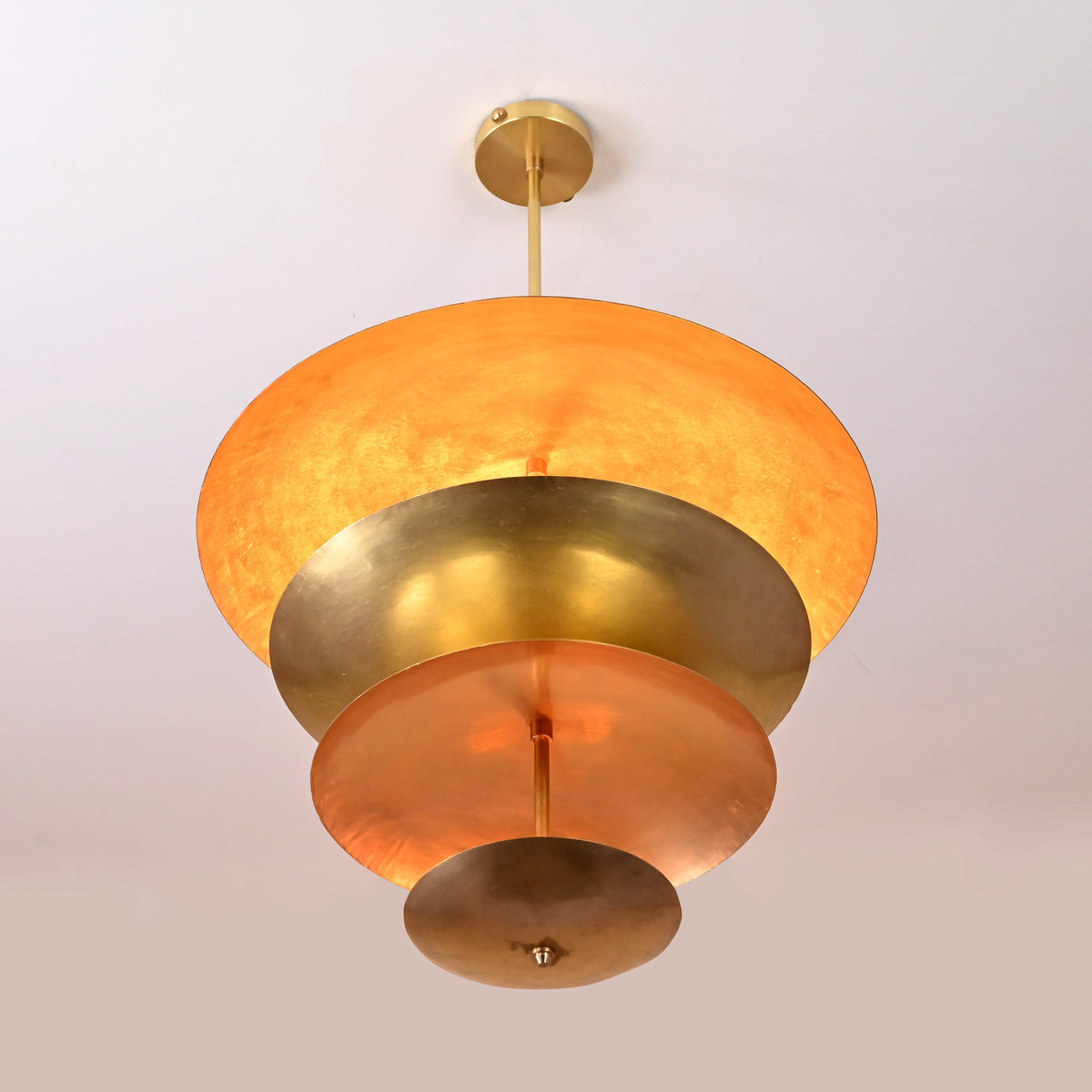 Bottom view of layered brass disc chandelier showing radiant hand-polished reflective surfaces