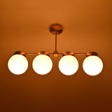 Night view of handcrafted brass linear chandelier with opal glass globes emitting warm, diffused lighting.