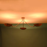 Luxury brass ceiling light with minimalist industrial design casting dramatic warm uplighting for refined interiors