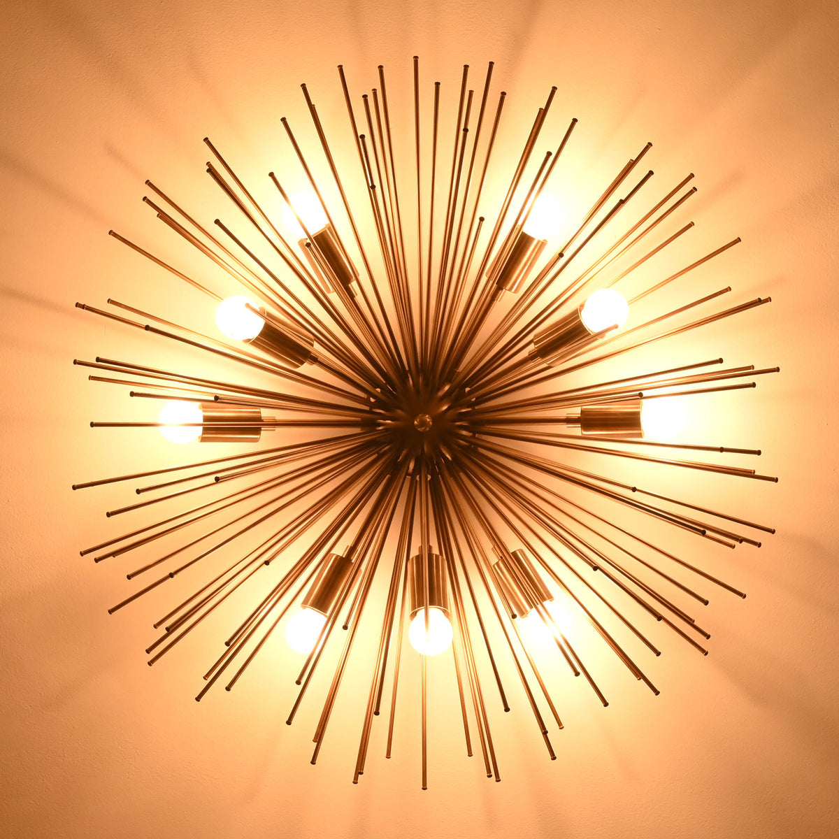 Luxury brass starburst flush mount ceiling light glowing warmly against dark ceiling