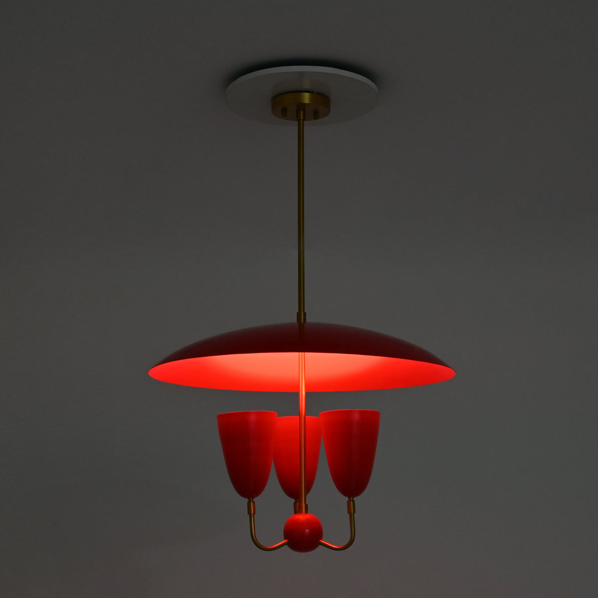 Three light red dome chandelier in full brass construction with enamel painted shades and decorative center ball