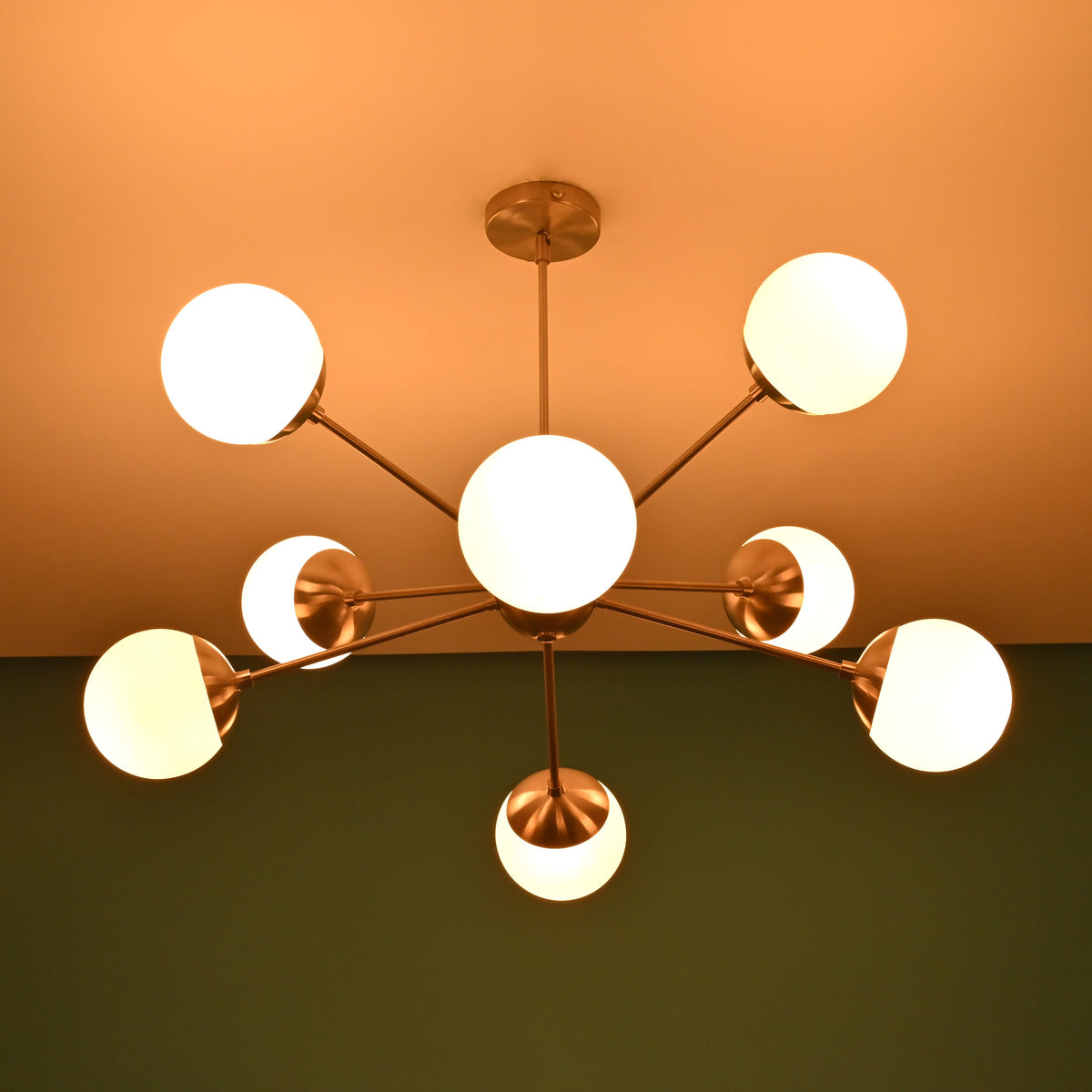 Mid century brass chandelier casting soft ceiling glow with opal glass globe shades